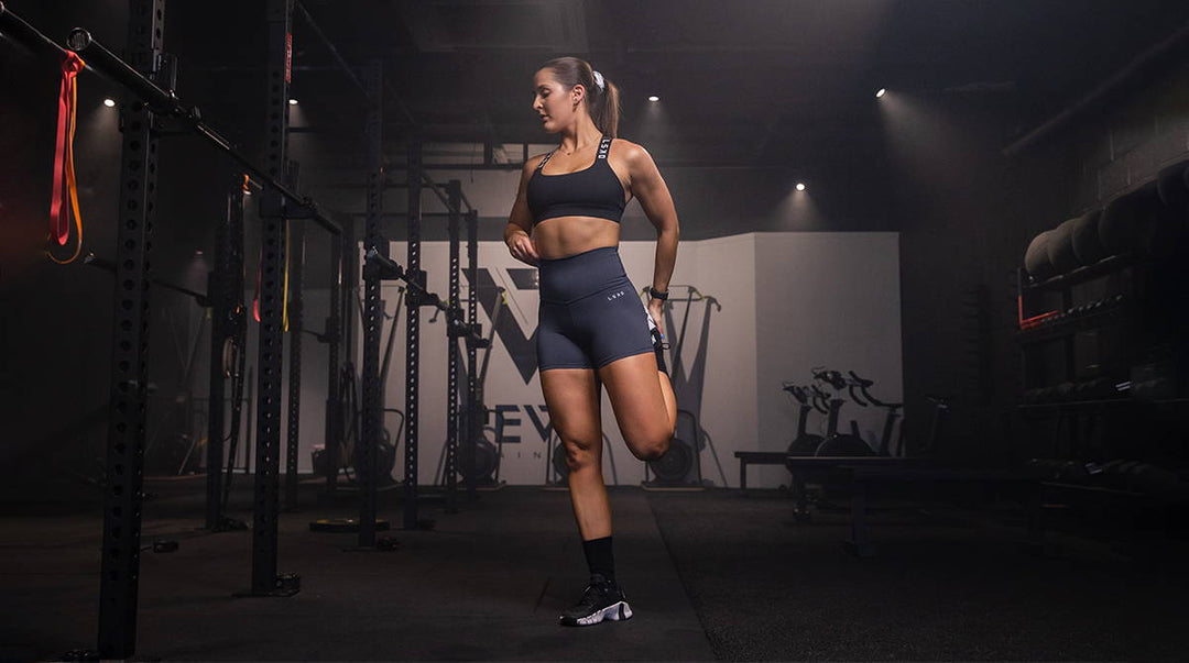 girl doing a quad stretch in the gym