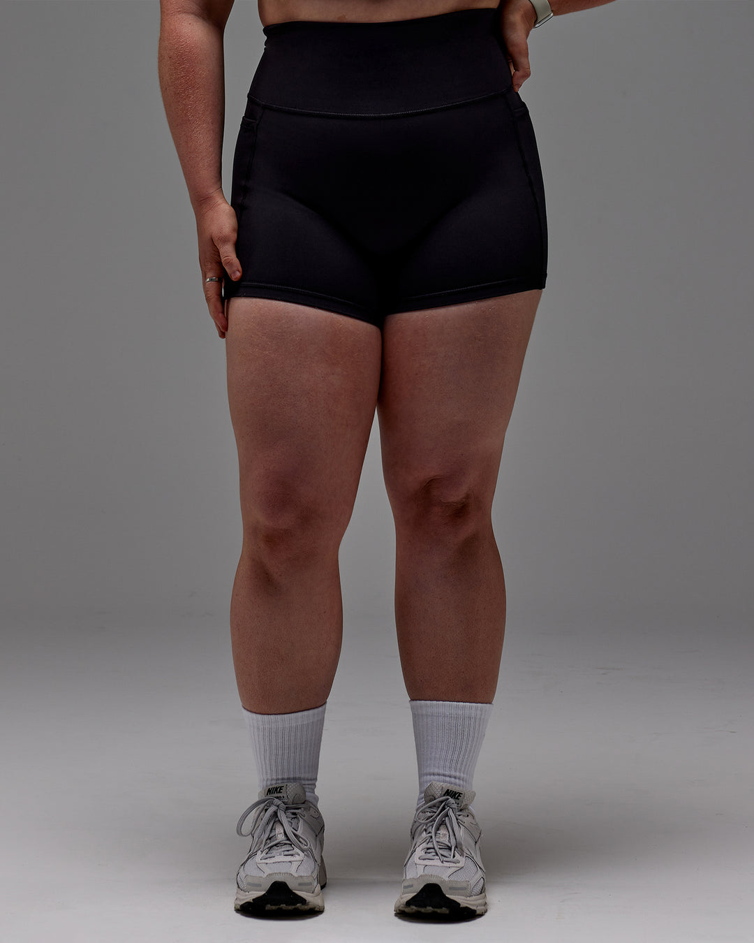 Woman wearing Fusion Ultra High-Rise 4" Short Pockets - Black | Model:Caity | Size:M