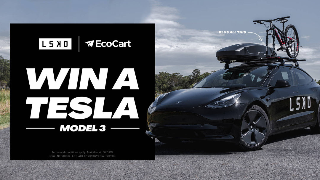 a tesla car parked with a bike on the roof