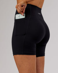 Woman wearing O.G. Fusion Ultra High-Rise 6" Short Pockets - Black | Model:Milly | Size:S