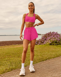 Woman wearing Velocity Sports Bra - Ultra Pink | Model:Zara | Size:2XS