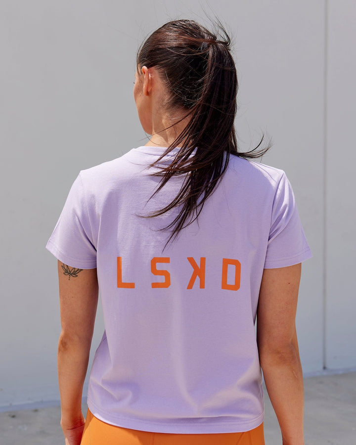 Woman wearing Endeavour FLX Cotton Tee - Pale Lilac-Impact Orange