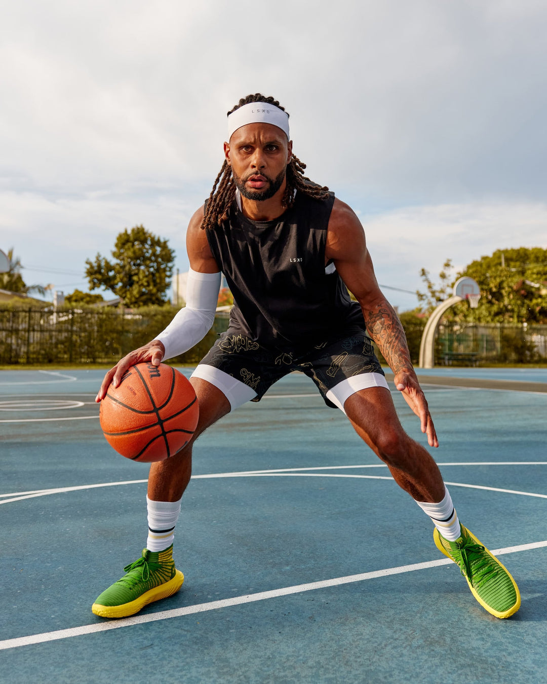 Man wearing Patty Mills Challenger 6" Performance Shorts - Black-Vital Green