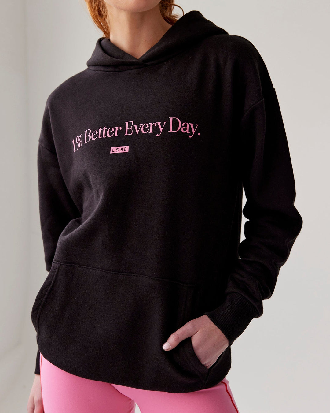 Woman wearing Unisex 1% Better Hoodie Oversize - Black-Pink Rose