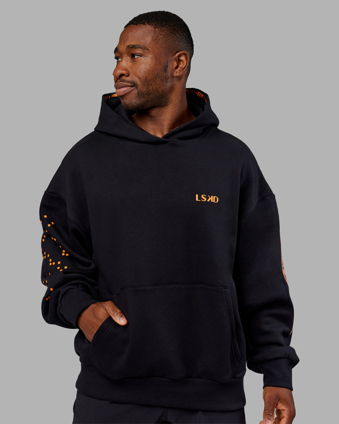 Man wearing Hyped Unisex Oversized Hoodie - Black-Vibrant Orange | Model:Sam | Size:L