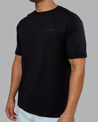 Man wearing RUN CLUB FLXCotton Tee Oversize - Black-Reflective | Model:Kaelyb | Size:L
