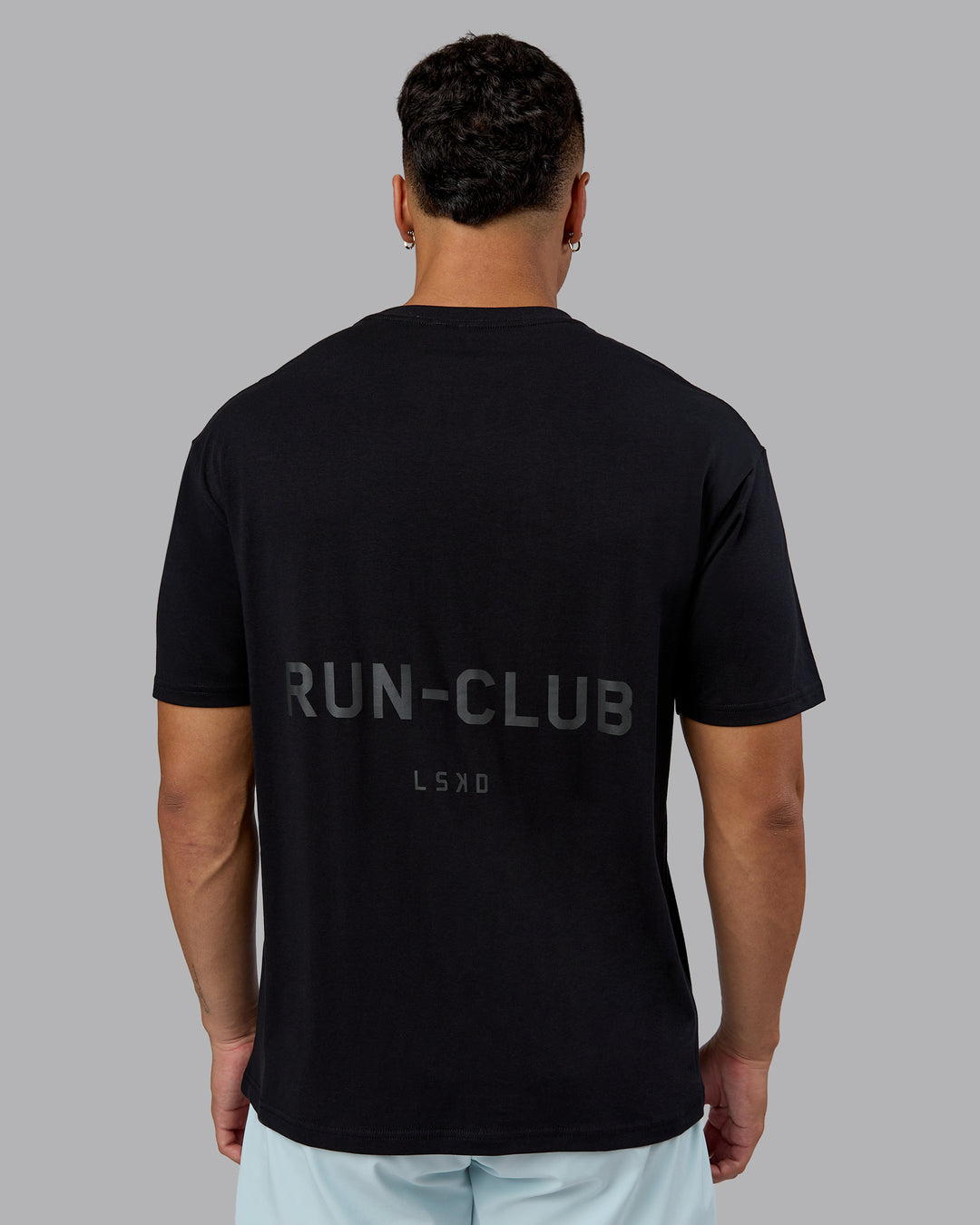 Man wearing RUN CLUB FLXCotton Tee Oversize - Black-Reflective | Model:Kaelyb | Size:L