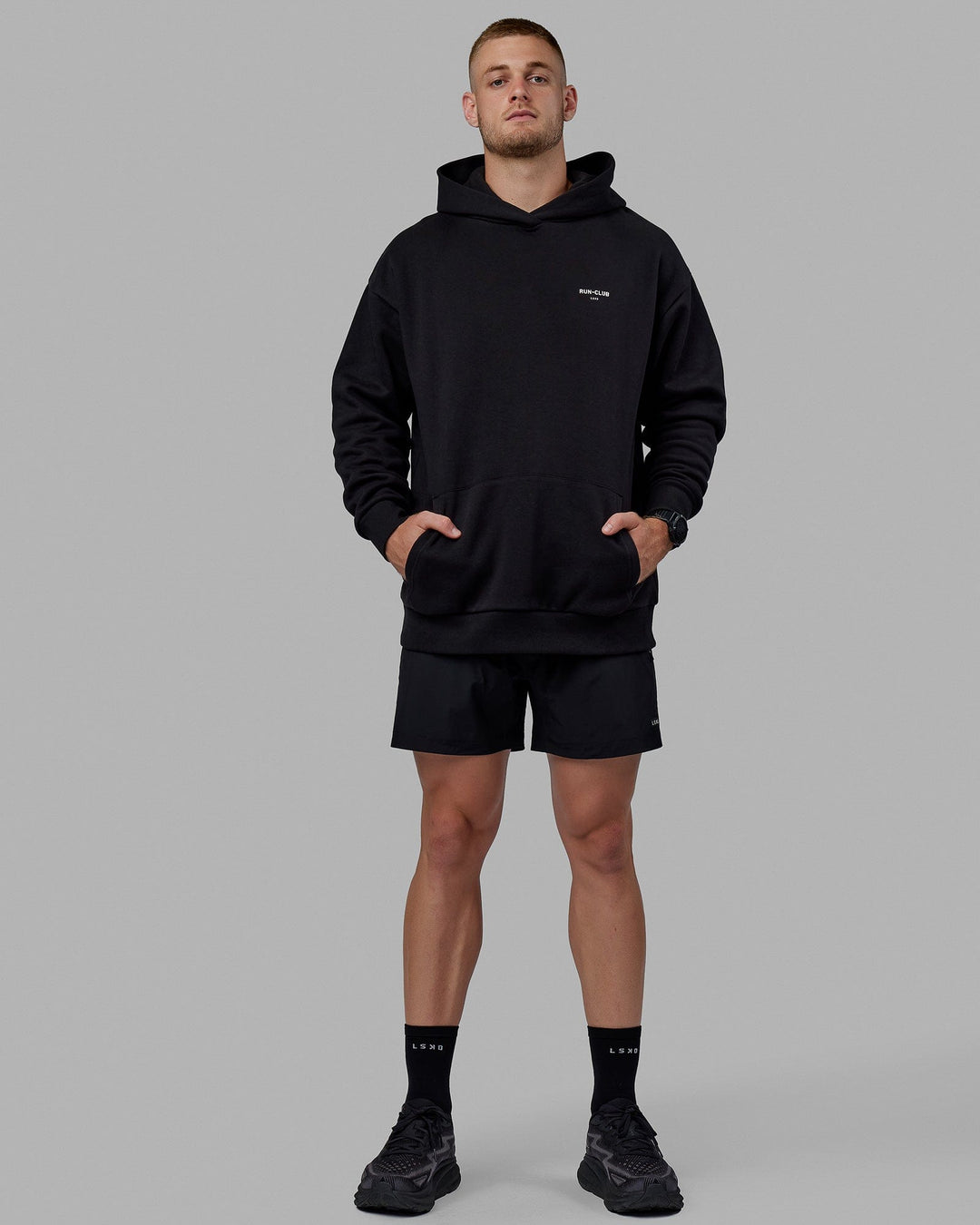 Man wearing Unisex RUN-CLUB Hoodie Oversize - Black