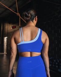 Woman wearing Thrive Asymmetric Sports Bra - Power Cobalt-Open Air | Model:Tiare | Size:M