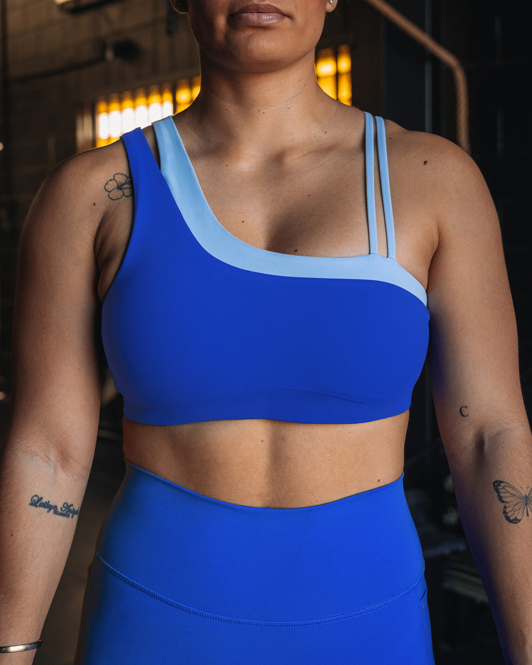 Woman wearing Thrive Asymmetric Sports Bra - Power Cobalt-Open Air | Model:Tiare | Size:M