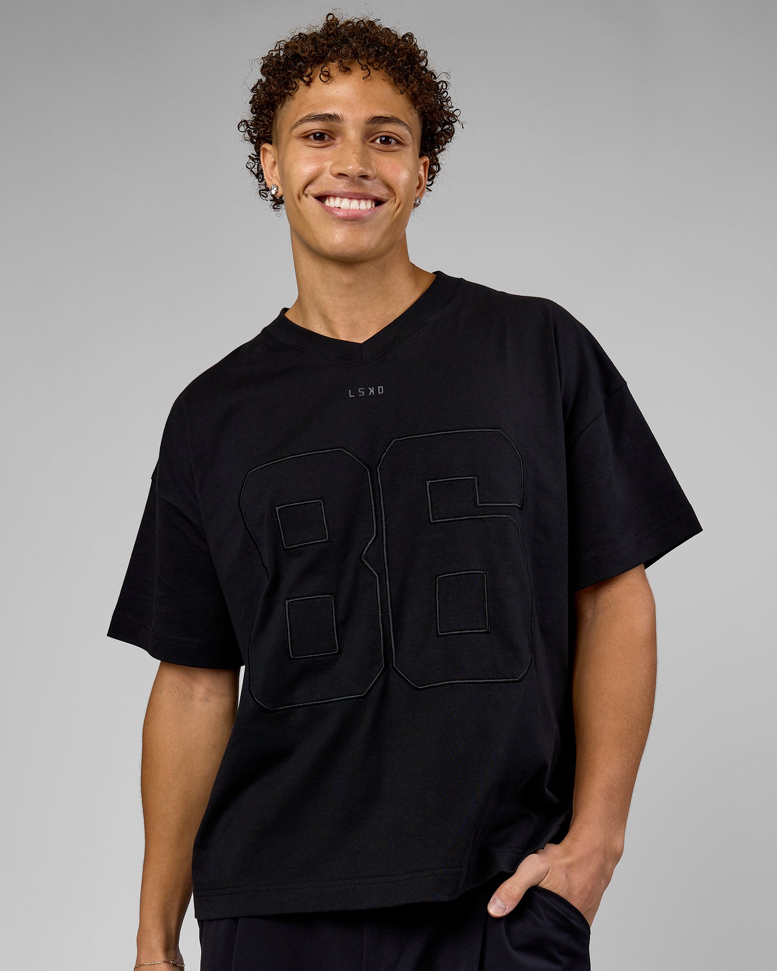 Man wearing 86 V-Neck Oversized Tee - Black-Black | Model:Leandro | Size:M