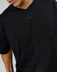 Man wearing 86 V-Neck Oversized Tee - Black-Black | Model:Leandro | Size:M