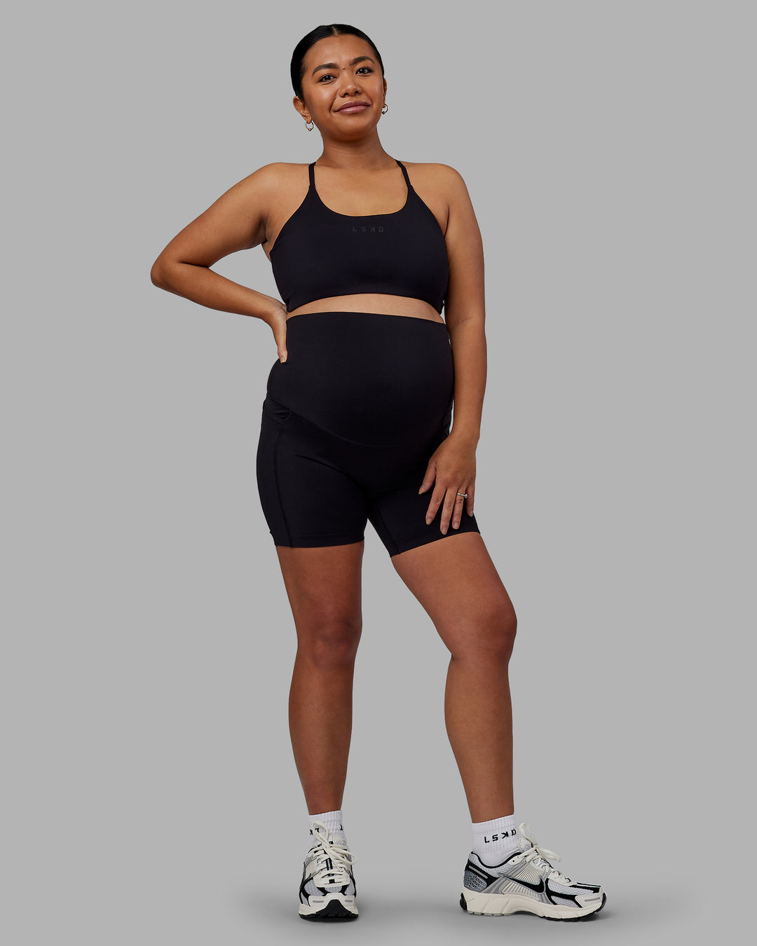 Woman wearing Elixir Ultra High-Rise Maternity 6&quot; Short Pockets - Black | Model:Jojo | Size:M
