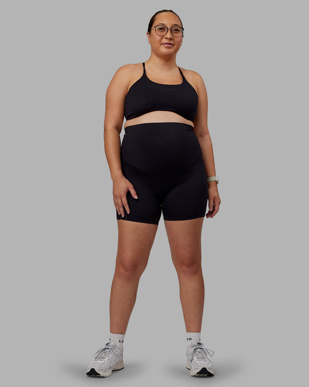 Woman wearing Elixir Ultra High-Rise Maternity 6&quot; Short Pockets - Black | Model:Nevada | Size:M