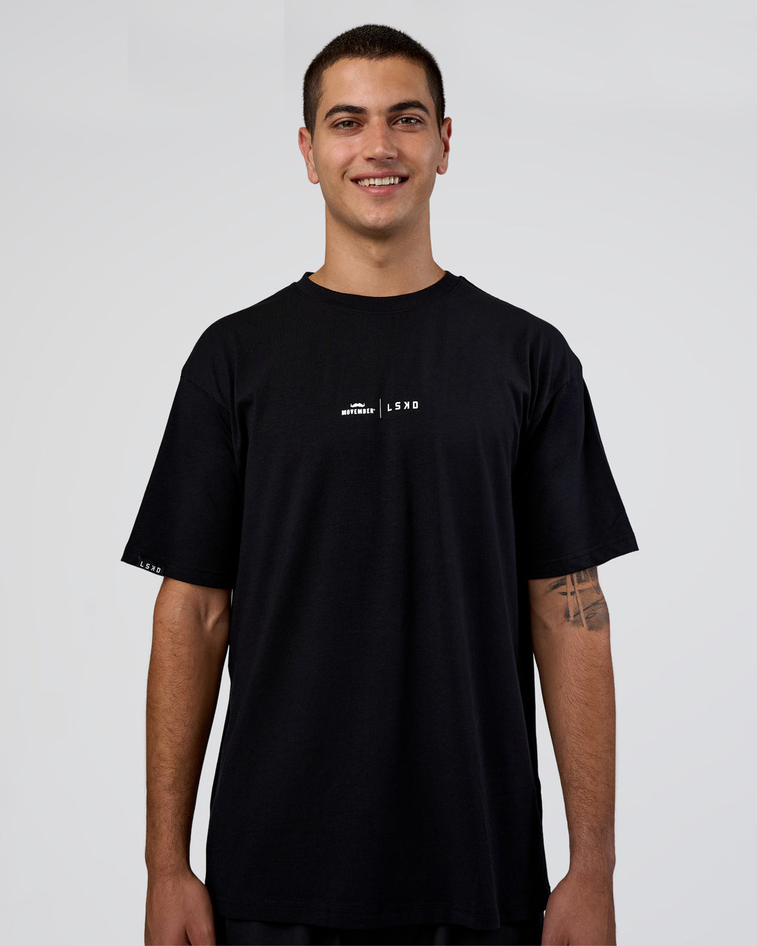 Man wearing Movember 2025 FLXCotton Oversize Tee - Black | Model:Zoran | Size:M