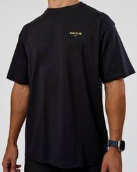 Man wearing RUN CLUB FLXCotton Tee Oversize - Black-Yellow Fizz | Model:Jaiden | Size:M