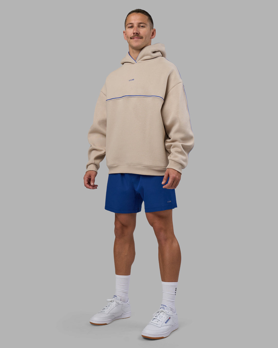 Man wearing Unisex Oversized Piping Hoodie - Shale Beige-Power Cobalt | Model:Jaiden | Size:M