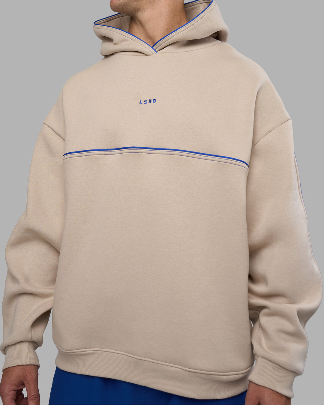Man wearing Unisex Oversized Piping Hoodie - Shale Beige-Power Cobalt | Model:Jaiden | Size:M