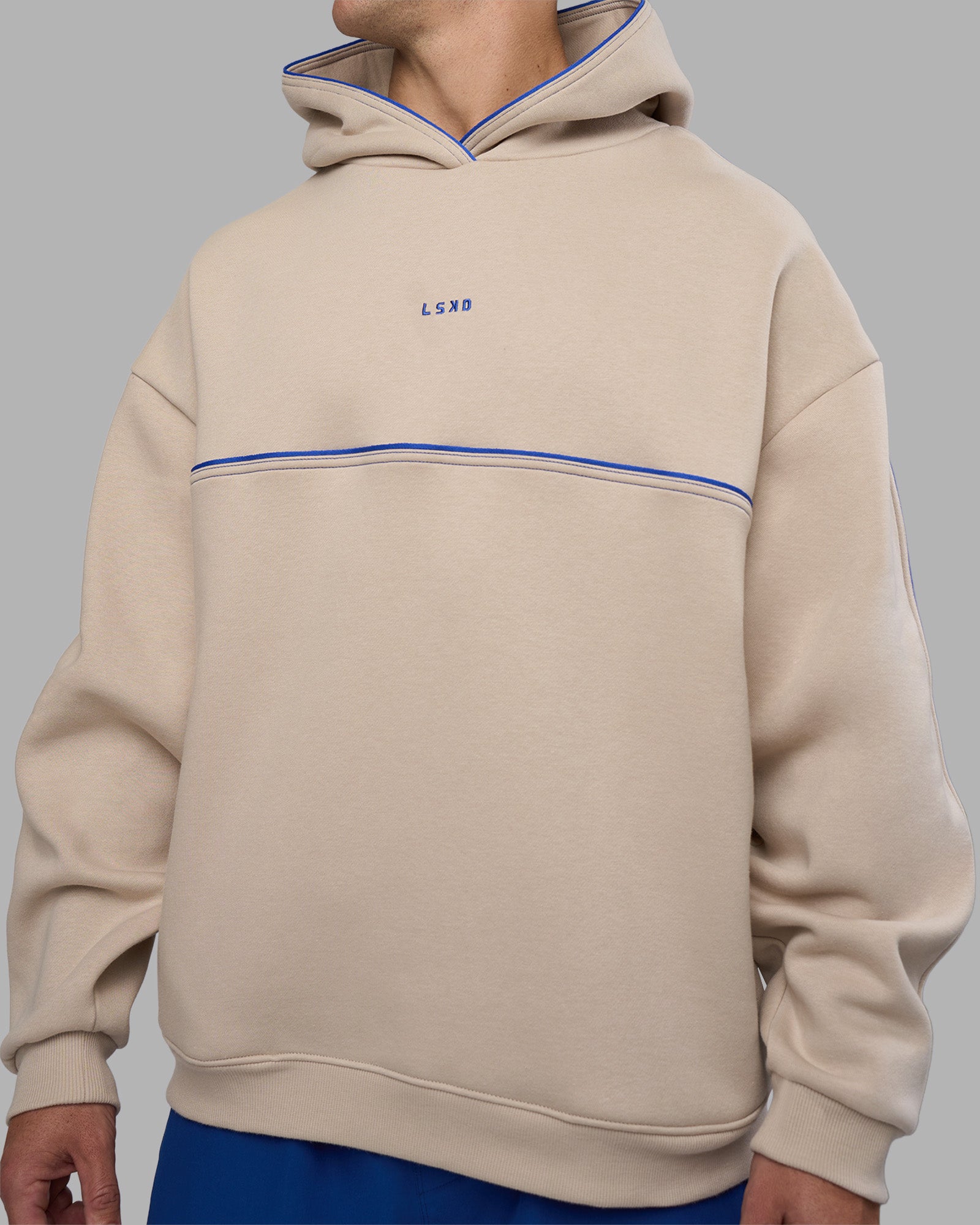 Man wearing Unisex Oversized Piping Hoodie - Shale Beige-Power Cobalt | Model:Jaiden | Size:M