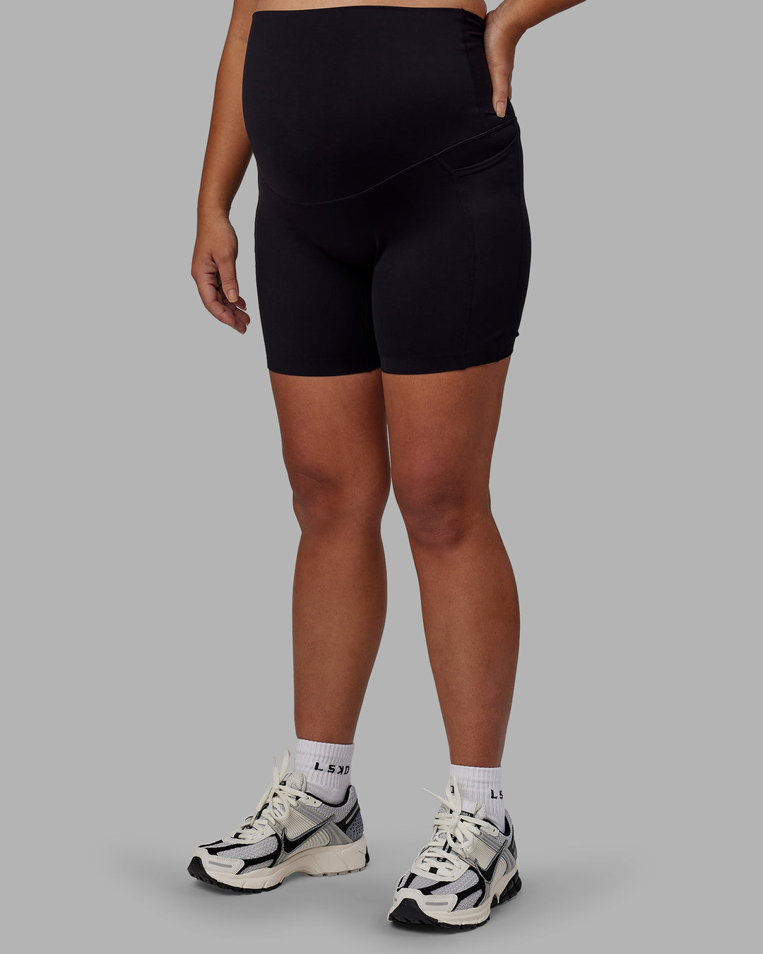 Woman wearing Elixir Ultra High-Rise Maternity 6&quot; Short Pockets - Black | Model:Jojo | Size:M