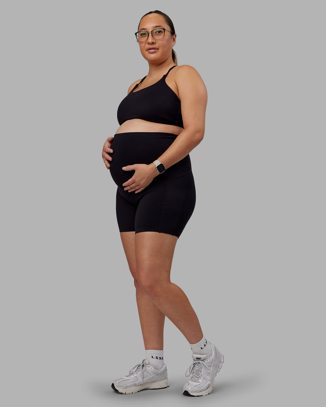 Woman wearing Elixir Ultra High-Rise Maternity 6&quot; Short Pockets - Black | Model:Nevada | Size:M