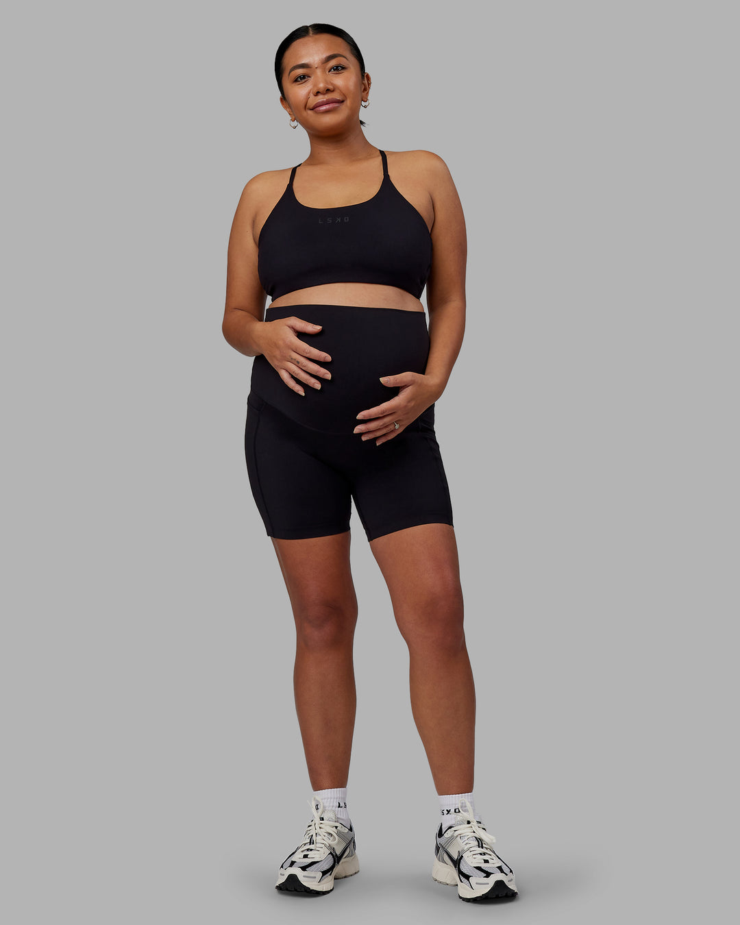 Woman wearing Elixir Ultra High-Rise Maternity 6&quot; Short Pockets - Black | Model:Jojo | Size:M
