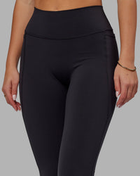 Woman wearing Fusion Ultra High-Rise Flared Legging Pockets - Black | Model:Milly | Size:S