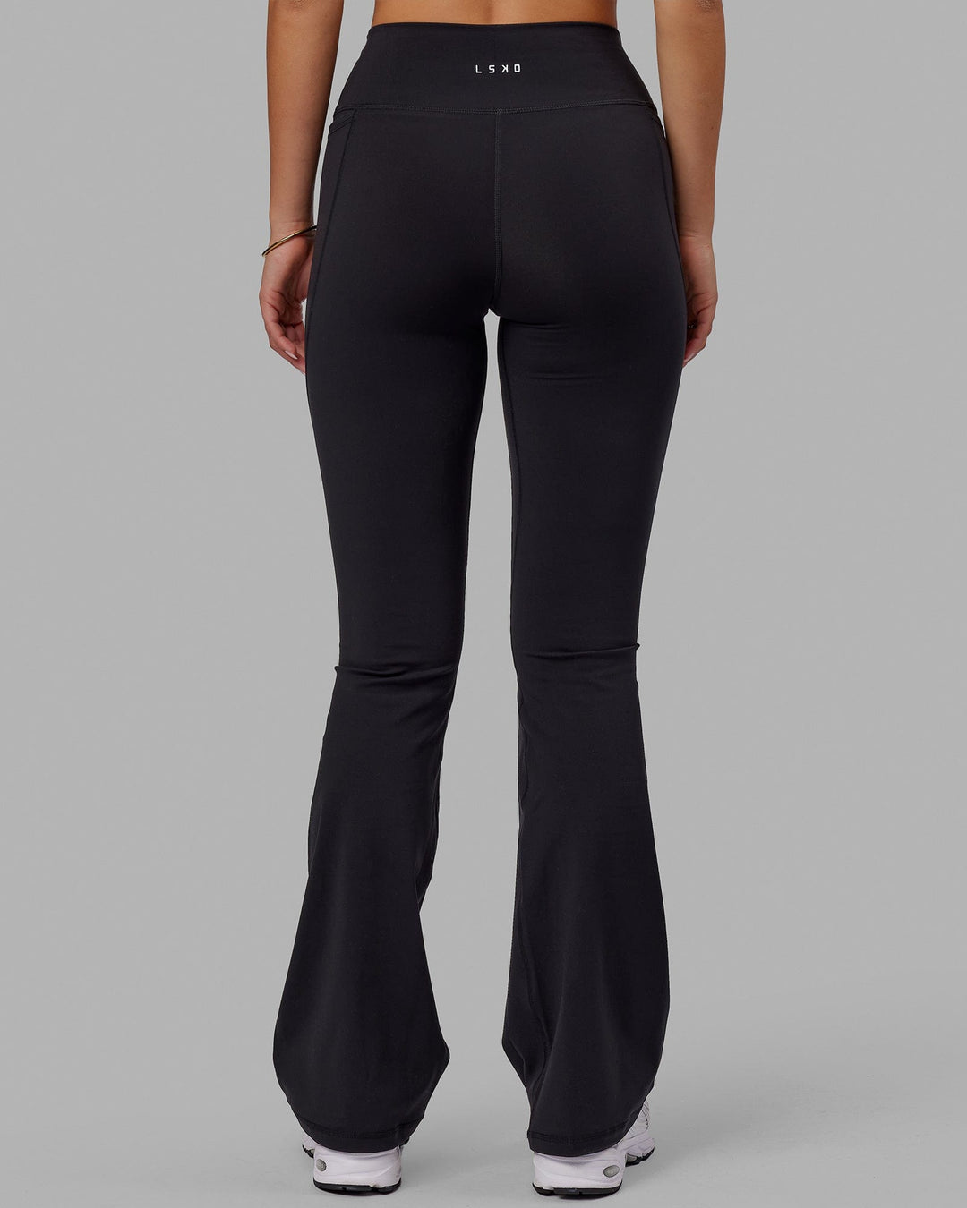 Woman wearing Fusion Ultra High-Rise Flared Legging Pockets - Black | Model:Milly | Size:S