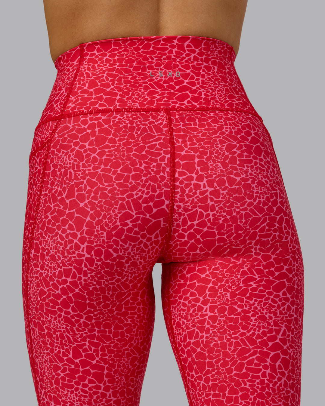 Woman wearing Fusion Ultra High-Rise 7/8 Legging Pockets - Red Vitality Print | Model:Halle | Size:S