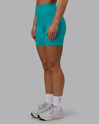 Woman wearing Fusion Ultra High-Rise 6" Short Pockets - Uplift Blue | Set:true | Angle:side | Model:Monique | Size:S