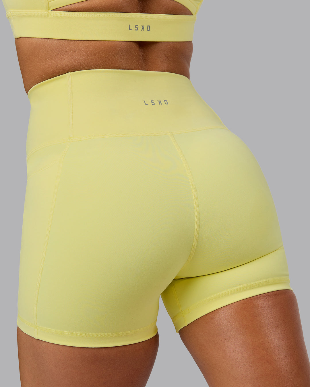 Woman wearing Fusion Ultra High-Rise 4&quot; Short Pockets - Lemon Fizz | Model:Shalem | Size:S