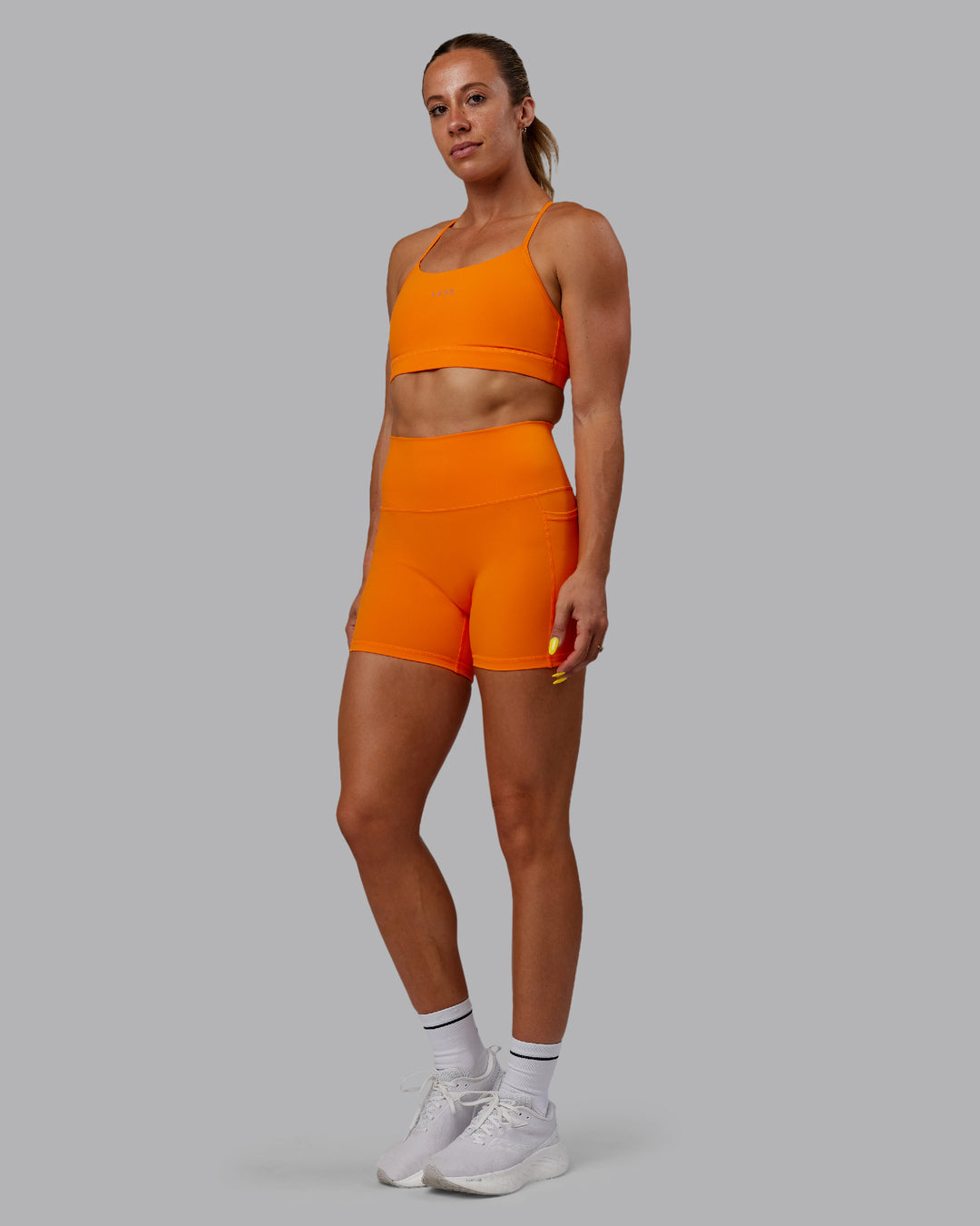 Woman wearing Fusion Ultra High-Rise 4&quot; Short Pockets - Vibrant Orange | Model:Bree | Size:S