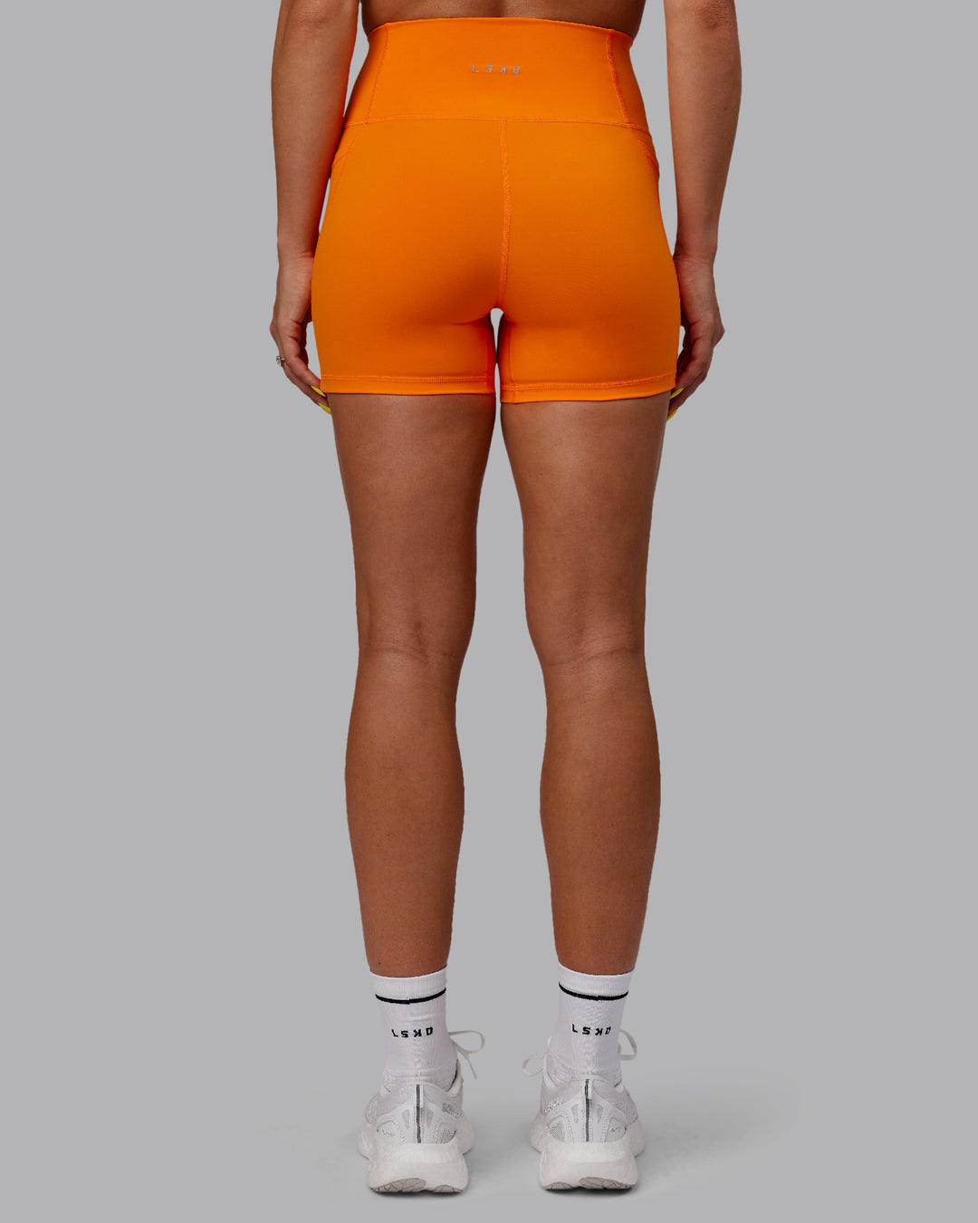 Woman wearing Fusion Ultra High-Rise 4&quot; Short Pockets - Vibrant Orange | Model:Bree | Size:S
