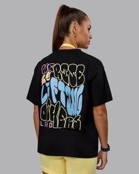 Woman wearing Go-To We Rise FLXCotton Oversized Tee - Black-Glacial Blue