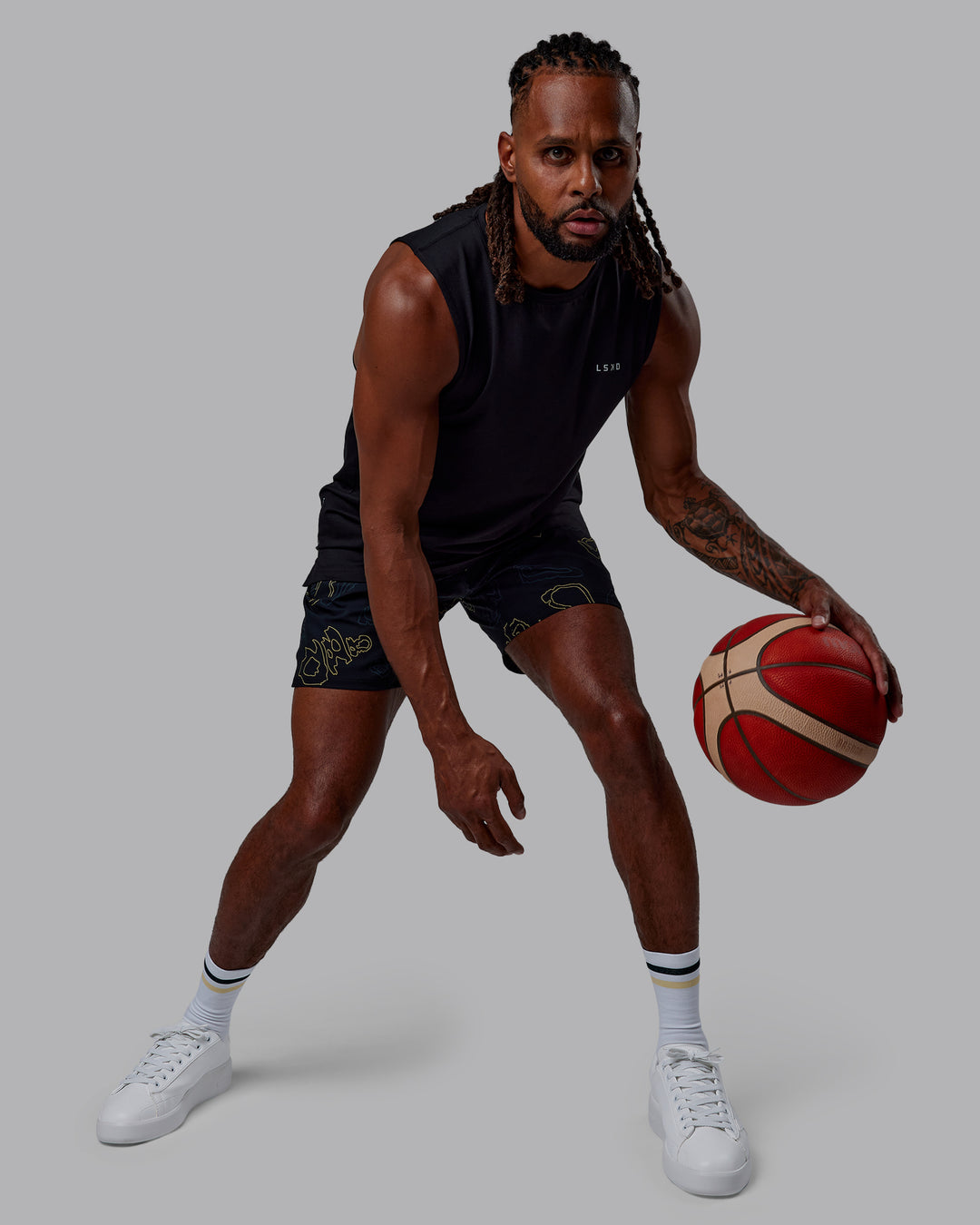Man wearing Patty Mills Challenger 6" Performance Shorts - Black-Vital Green