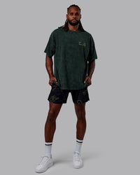Man wearing Patty Mills Challenger 6" Performance Shorts - Black-Vital Green