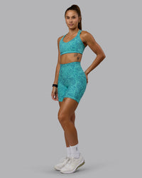Woman wearing Push The Limit Sports Bra - Aquatic Awe Vitality Print