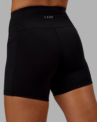 Woman wearing O.G. Rep Ultra High-Rise 4" Short Pockets - Black-Black | Model:Abbey| Size:S
