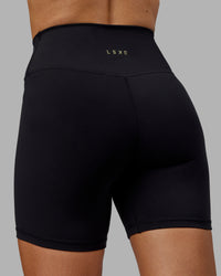 Woman wearing Sara Strike Ultra High-Rise Cross Over Waist 6" Short - Black