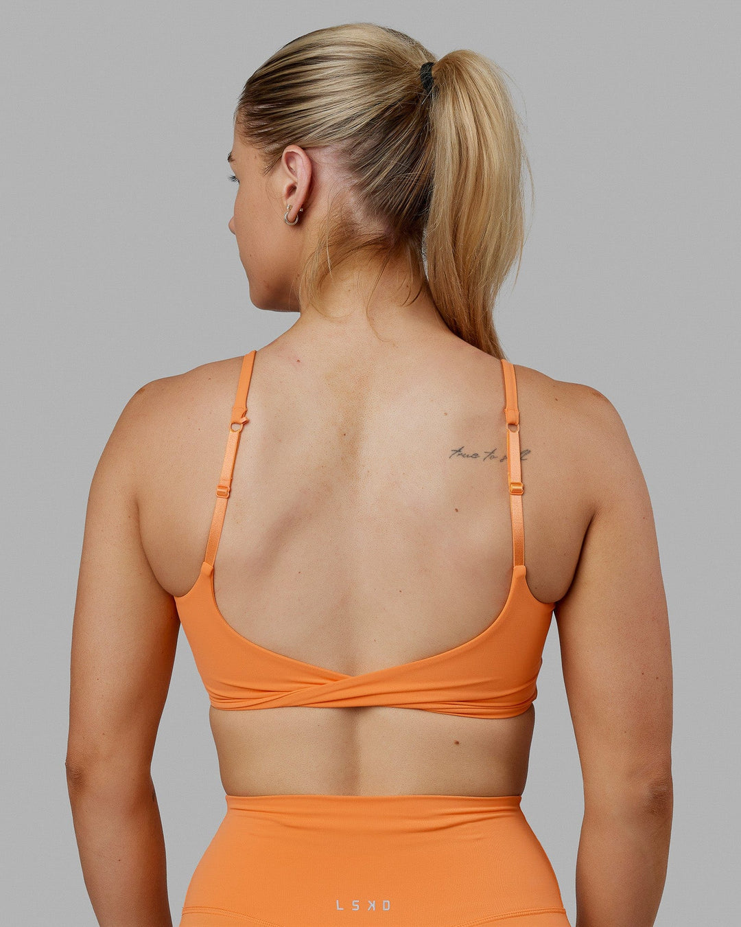 Woman wearing Twist Sports Bra - Tangerine