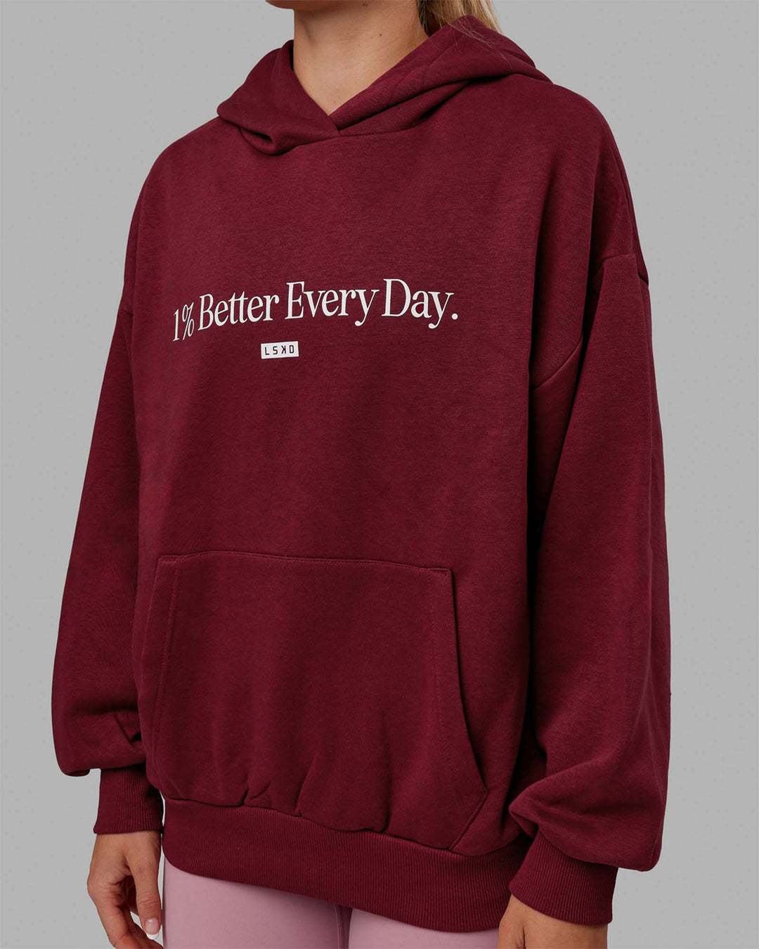 Woman wearing Unisex 1% Better Hoodie Oversize - Cranberry-White