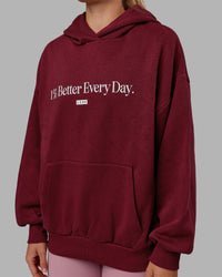 Woman wearing Unisex 1% Better Hoodie Oversize - Cranberry-White