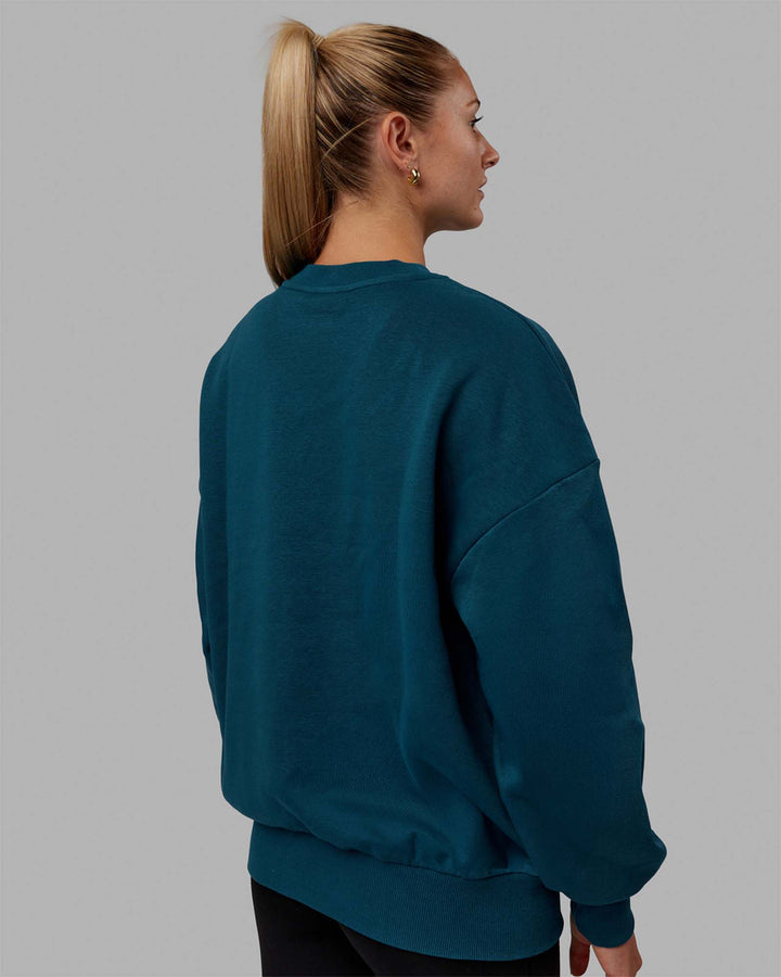 Woman wearing Unisex 1% Better Sweater Oversize - Deep Lagoon-White