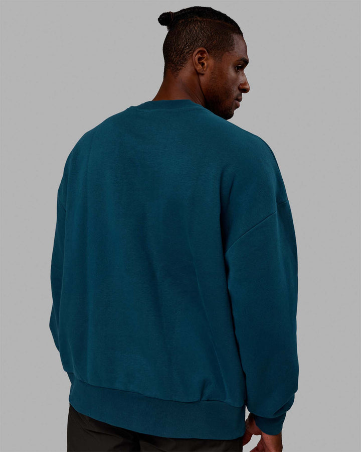 Man wearing Unisex 1% Better Sweater Oversize - Deep Lagoon-White