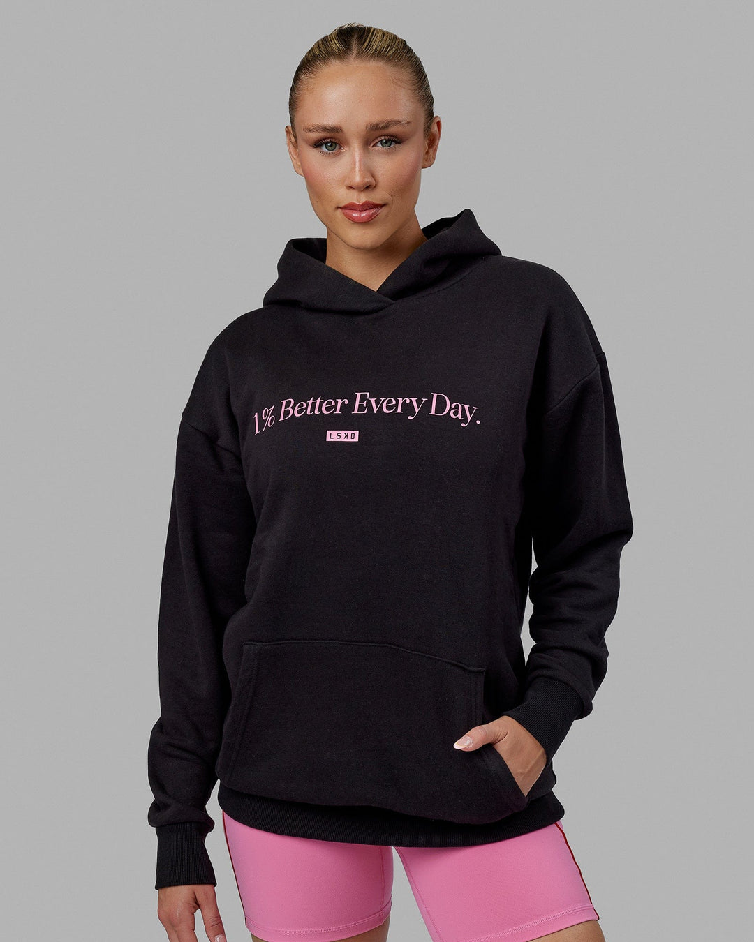 Woman wearing Unisex 1% Better Hoodie Oversize - Black-Pink Rose