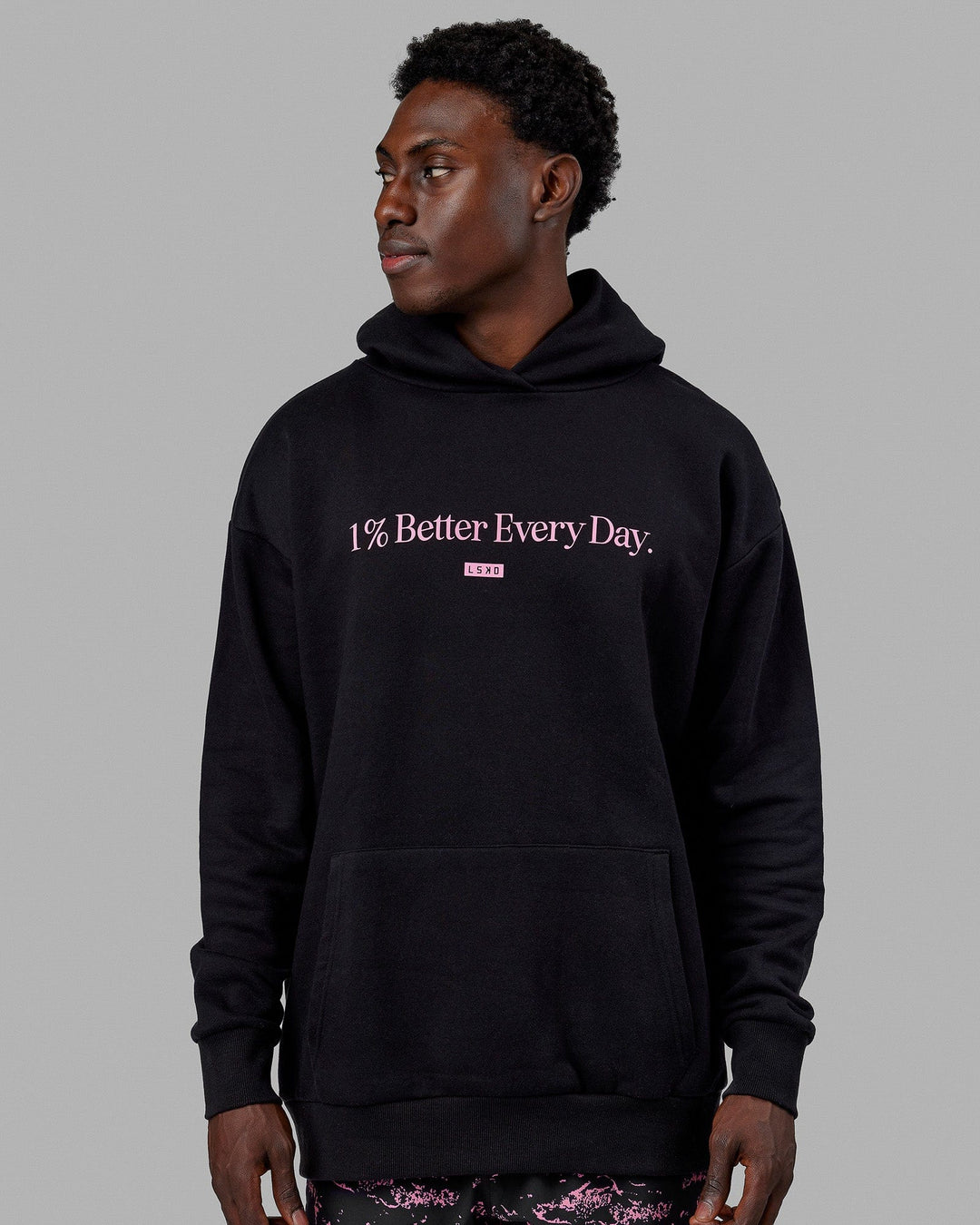 Man wearing Unisex 1% Better Hoodie Oversize - Black-Pink Rose