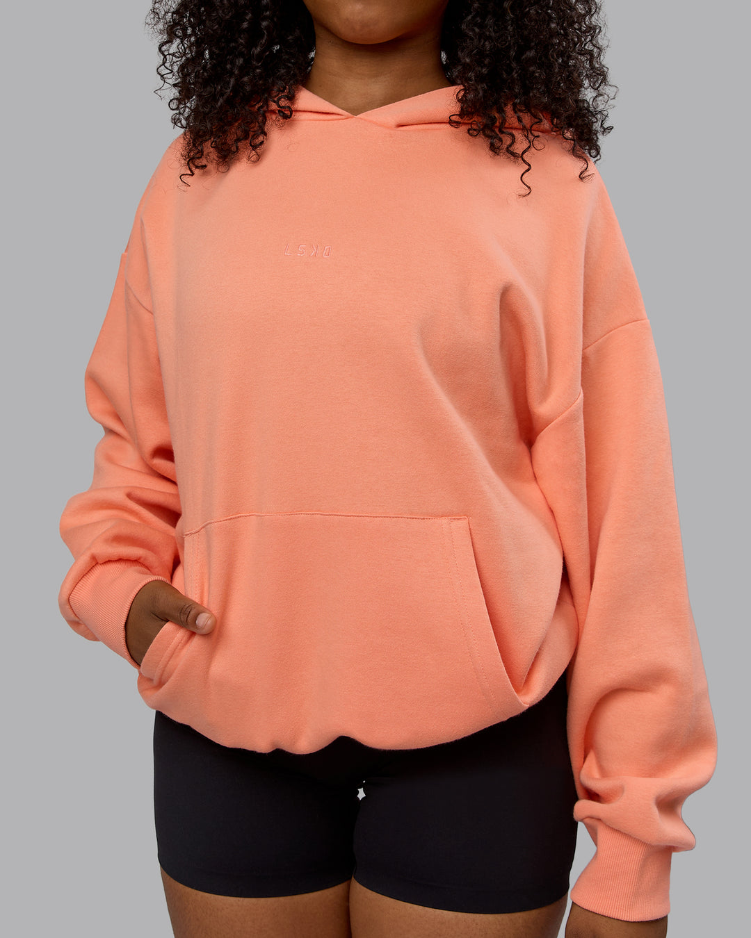 WOman wearing Unisex MVP Hoodie Oversize - Mellow Peach