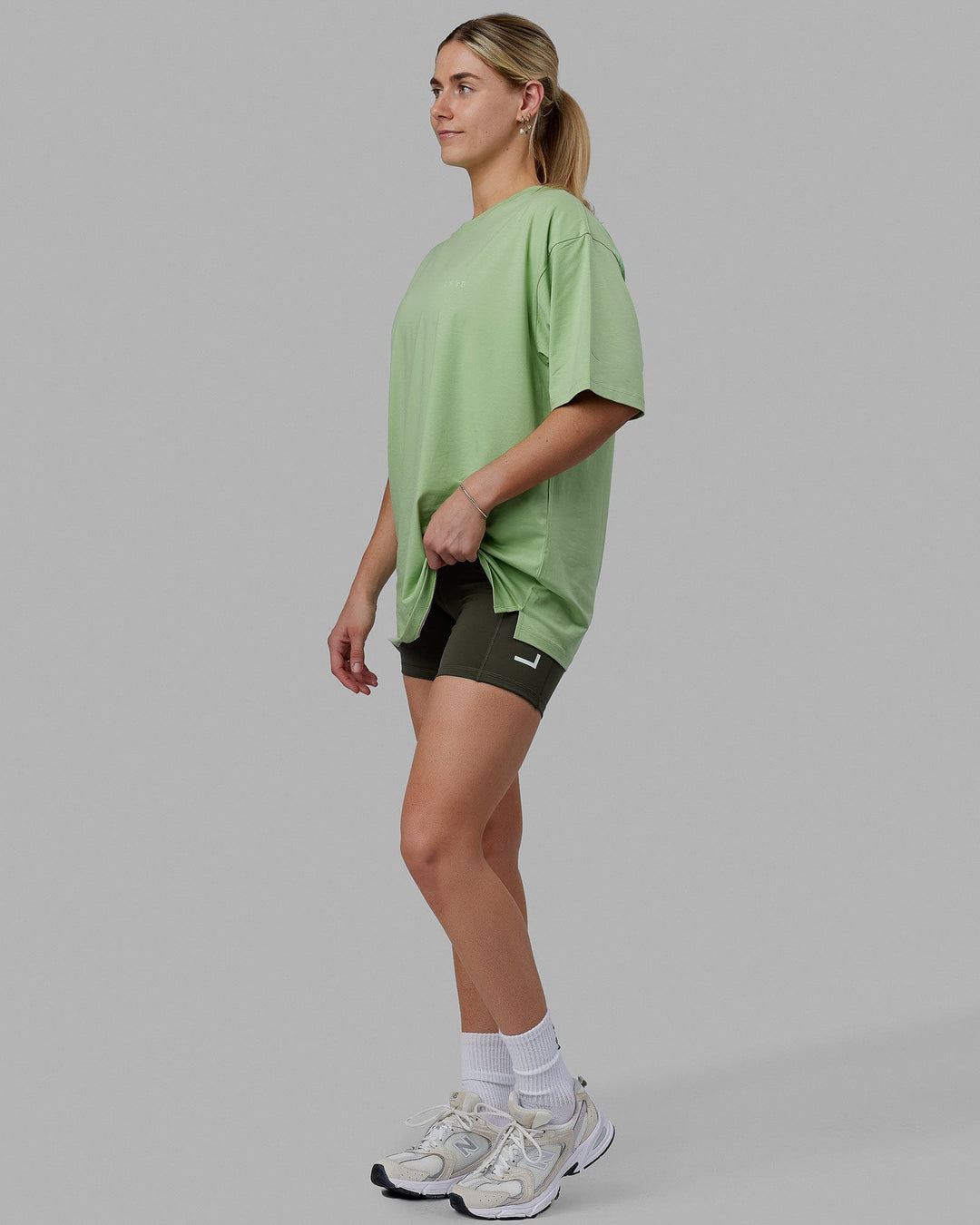Woman wearing Unisex PimaFLX Tee Oversize - Green Fig
