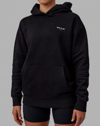 Woman wearing Unisex RUN-CLUB Hoodie Oversize - Black