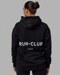 Woman wearing Unisex RUN-CLUB Hoodie Oversize - Black